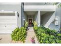 Inviting front entryway with a wooden door, green plants, and manicured shrubs at 1594 Cassius St, Lutz, FL 33549