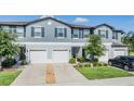 Charming townhome featuring a gray exterior, white garage doors, and well-maintained landscaping at 1594 Cassius St, Lutz, FL 33549