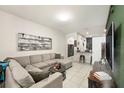 Inviting living room featuring a comfortable gray sectional sofa, tile floors, and modern décor at 2140 Laceflower Dr, Brandon, FL 33510