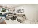 Cozy living room showcasing a gray sectional sofa, tile floors, and access to the dining area at 2140 Laceflower Dr, Brandon, FL 33510