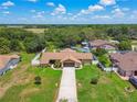 Expansive aerial view of a one-story home with a fenced yard and a long driveway in a lush, green neighborhood at 2436 Covington Ave, Spring Hill, FL 34608