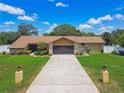 Inviting one-story home showcasing a long driveway, two-car garage, stone accents, and a lush, green lawn at 2436 Covington Ave, Spring Hill, FL 34608
