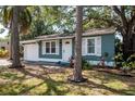 Quaint single-story home featuring blue siding, white trim, and mature trees in a landscaped yard at 2616 47Th N Ave, St Petersburg, FL 33714