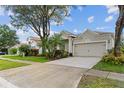 Inviting home showcasing a two-car garage, lush landscaping with palm accents, and a well-maintained lawn at 5628 Terrain De Golf Dr, Lutz, FL 33558