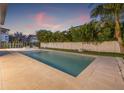 Backyard swimming pool features a modern design, travertine pavers, and privacy landscaping and fence at 5964 Bayview S Cir, St Petersburg, FL 33707