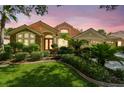 Charming home featuring mature landscaping, a clay tile roof, and a welcoming entrance at dusk at 10229 Waterside Oaks Dr, Tampa, FL 33647