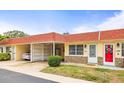 Charming condo featuring a red roof, well-manicured landscaping, and convenient carport at 230 Portree Dr, Dunedin, FL 34698