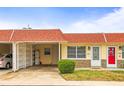 Charming condo featuring a red roof, well-manicured landscaping, and a convenient carport at 230 Portree Dr, Dunedin, FL 34698
