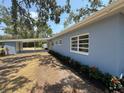 Side of the home featuring a convenient carport, freshly painted walls, and vibrant red flowers at 3000 58Th S Ave, St Petersburg, FL 33712