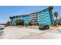 Bright blue condo building with ample parking and lush palm trees, offering a vibrant living space at 3315 58Th S Ave # 605, St Petersburg, FL 33712