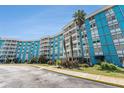 Bright blue condo building with white balconies offering a vibrant living space with lush, tropical landscaping at 3315 58Th S Ave # 605, St Petersburg, FL 33712