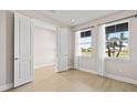 Bright bedroom featuring neutral walls, wood floors, and two large windows with views of the outdoors at 34307 Radley Way, Wesley Chapel, FL 33545