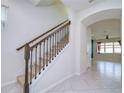 Elegant staircase featuring an iron railing, carpeted steps, and an arched entryway at 5933 Caldera Ridge Dr, Lithia, FL 33547