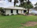 Charming single-story home with a metal roof, a well-manicured lawn, and a covered car in the driveway at 6488 Robinswood Ave, Brooksville, FL 34602