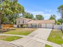 Lovely two-story home with a two-car garage, mature trees, and a well-manicured front lawn at 6607 Larimer Dr, Tampa, FL 33615