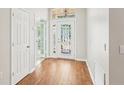Bright foyer featuring wood flooring, a decorative glass front door with transom window, and white trim at 10150 Heather Sound Dr, Tampa, FL 33647