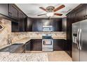 Stylish kitchen with stainless steel appliances, a tiled backsplash, granite countertops, and dark wood cabinets at 1103 Old Mill Pond Rd, Palm Harbor, FL 34683