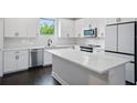 Bright kitchen features white cabinets, modern appliances, subway tile backsplash, and large island with quartz countertop at 1316 W Carmen St # 2, Tampa, FL 33606