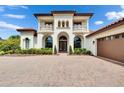 Mediterranean-style home with a red tile roof, arched entryways, a spacious driveway, and well-maintained landscaping at 16406 Chapman Crossing Dr, Lithia, FL 33547