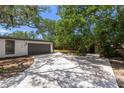 Spacious two-car garage with a modern gray door and a concrete driveway, shaded by mature trees, offering convenience at 2157 20Th Sw Ave, Largo, FL 33774