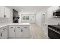 Modern kitchen featuring white cabinets, stainless steel appliances, and sleek countertops, seamlessly flowing into the living area at 2157 20Th Sw Ave, Largo, FL 33774