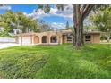 Inviting single-story home featuring a well-manicured lawn and arched entryway at 30 Pinetree Ct, Palm Harbor, FL 34683