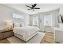 Bright main bedroom with hardwood floors, a ceiling fan, and natural light from two windows at 4757 Legacy Park Dr, Tampa, FL 33611