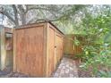 Wooden storage shed with a metal roof, surrounded by greenery and a brick pathway at 7107 Colonial Lake Dr, Riverview, FL 33578