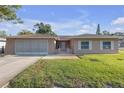 Charming single-story home featuring a well-manicured lawn, shutters, and an attached garage at 12817 Lake Tree Ln, Hudson, FL 34669