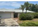 Inviting home featuring mature palm trees, an attached garage, and a well-maintained lawn at 1445 72Nd Ne Ave, St Petersburg, FL 33702