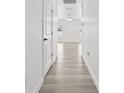 Bright hallway with wood-look floors, leading to a view of windows at the end at 14498 Whitewater Way, Brooksville, FL 34604