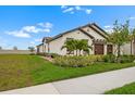 Attractive single-story home with a well-manicured lawn and lush landscaping at 17222 Holly Well Ave, Wimauma, FL 33598