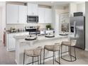 Modern kitchen featuring white cabinets, stainless steel appliances, and a granite island with stylish bar seating at 1877 Brekey Way, Zephyrhills, FL 33541