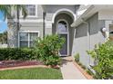 Close-up of a home's front door featuring an arched entryway and lush landscaping at 20102 Oakflower Ave, Tampa, FL 33647