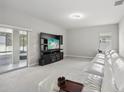 Spacious living room featuring a large white couch, entertainment center, and sliding glass doors at 20102 Oakflower Ave, Tampa, FL 33647