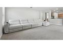 Bright living room featuring a large white sectional couch, carpeted floors and neutral paint at 20102 Oakflower Ave, Tampa, FL 33647