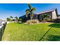 Expansive backyard with lush green grass, palm trees and partial view of the home at 2100 Aqui Esta Dr, Punta Gorda, FL 33950