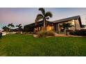 Expansive backyard with lush green grass, palm trees and partial view of the home at 2100 Aqui Esta Dr, Punta Gorda, FL 33950