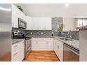Modern kitchen featuring white cabinets, granite countertops, stainless steel appliances, and decorative backsplash at 2604 E Chelsea St, Tampa, FL 33610