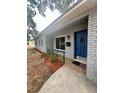 A tidy gray brick home with an updated blue front door, landscaping, and an inviting brick porch at 306 Oak Ave, Brandon, FL 33510