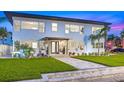 Beautiful two-story home with well-manicured lawn, tropical plants and tiled entryway at dusk at 650 70Th Ave, St Pete Beach, FL 33706