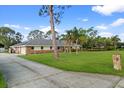View of the house and long driveway with well-kept lawn and mature trees on a sunny day at 903 Tomahawk Trl, Brandon, FL 33511