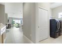 Hallway leading to the living area and featuring a laundry closet with a modern washer and dryer at 10153 Spruce River Way, Parrish, FL 34219