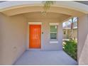 Inviting covered entry featuring a bright orange front door and charming architectural details at 10210 White Linen Ave, Riverview, FL 33578
