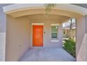 Inviting front porch featuring a vibrant orange door with sidelight and neutral-toned exterior at 10210 White Linen Ave, Riverview, FL 33578