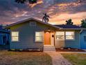 Charming single-story home features a stone walkway, light green siding, with a sunset sky in the background at 1267 Woodlawn Ter, Clearwater, FL 33755