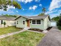 Inviting single-story home with light green siding, a well-manicured lawn, and a detached garage at 1267 Woodlawn Ter, Clearwater, FL 33755