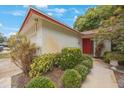 Inviting entrance with red door, mature landscaping, and a charming walkway at 13563 Cordova Dr, Largo, FL 33774