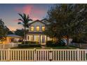 Charming two-story home with a manicured lawn, white picket fence, and inviting front entrance at dusk at 1436 30Th N Ave, St Petersburg, FL 33704