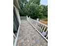 Outdoor patio with stone-look tiles, white railings, and views of the backyard and surrounding trees at 144 Douglas W Rd # F, Oldsmar, FL 34677